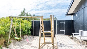 A wooden deck with a swing set and a ladder, surrounded by a fence and greenery. - 4 Star Holiday Home in Henne (Henne)