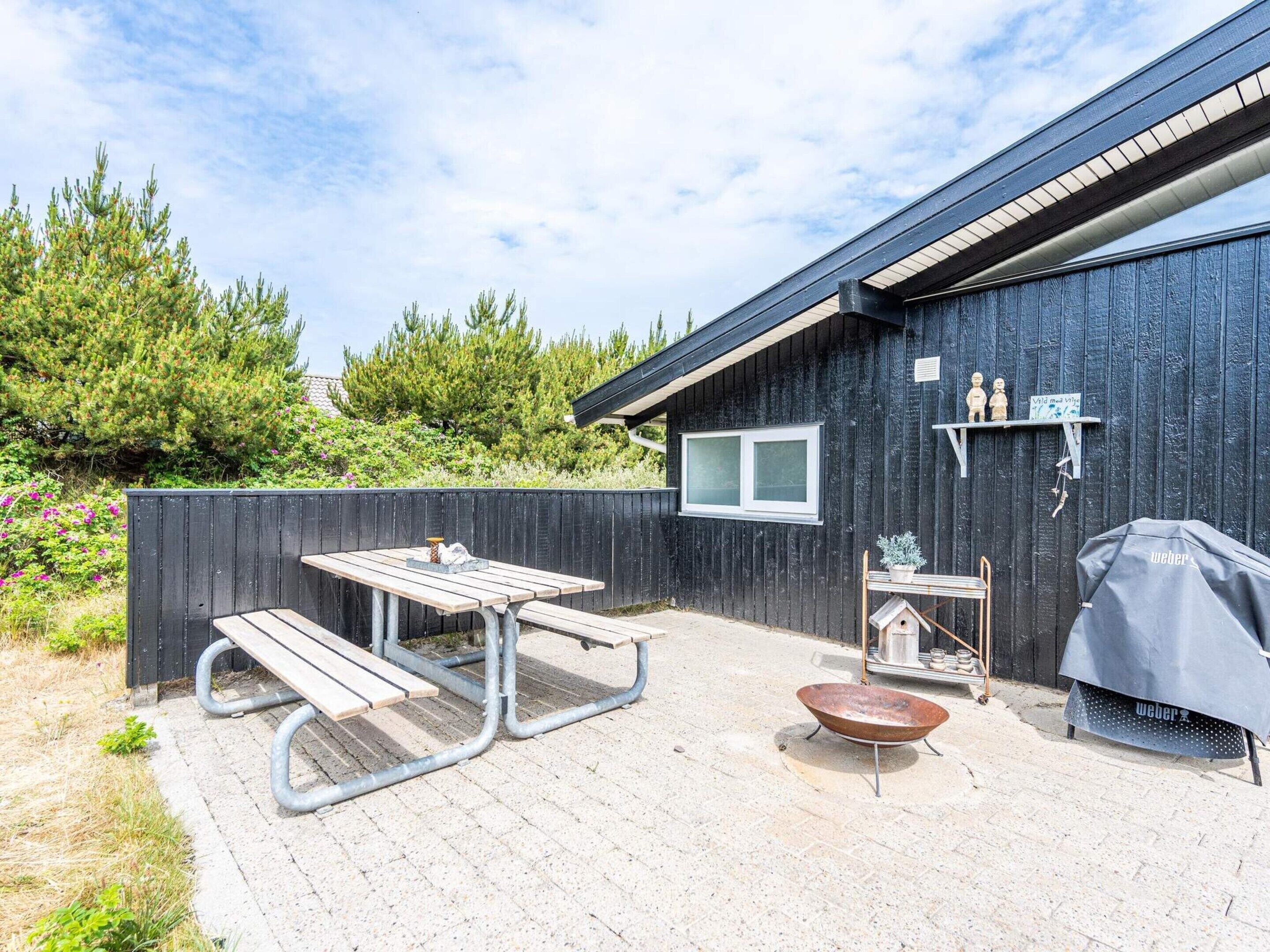 A patio area with a picnic table, a barbecue grill, and a birdhouse.