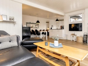 A modern living room with a sofa, a wooden coffee table, and a television. - 4 Star Holiday Home in Henne (Henne)