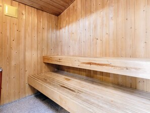 A wooden sauna with benches and a visible light switch on the wall. - 4 Star Holiday Home in Henne (Henne)
