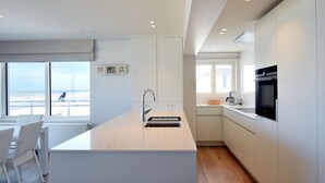 Una cucina moderna con isola centrale, mobili bianchi e vista sulla spiaggia.