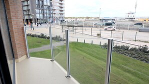 Un balcon donnant sur un parking et des immeubles.