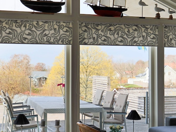 A sunlit patio with a table and chairs, a decorative sailboat, and a view of a residential area.