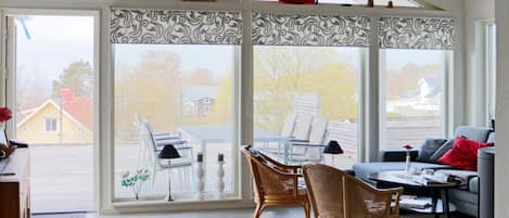 A sunroom with large windows, wicker furniture, and model ships.