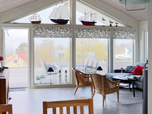 A sunroom with large windows, wicker furniture, and model ships. - 5 Star Holiday Home in Steninge (Steninge)