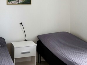 A simple room with a single bed, a bedside table with a lamp, and a small drawer. - 5 Star Holiday Home in Steninge (Steninge)