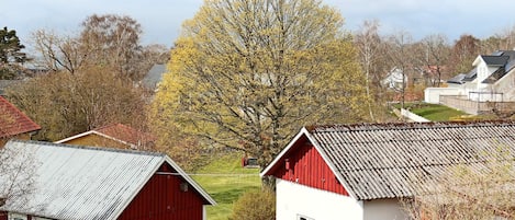 A rural landscape with red and white buildings, a large tree, and a clear sky.