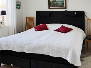 A bed with a dark headboard, white bedding, and two red pillows. - 5 Star Holiday Home in Steninge (Steninge)