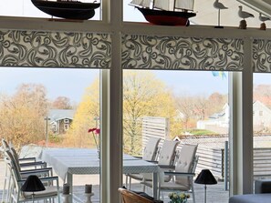 A covered outdoor seating area with chairs and tables, overlooking a residential neighborhood. - 5 Star Holiday Home in Steninge (Steninge)