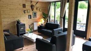Una sala de estar acogedora con chimenea, paredes de madera y un ventanal grande.