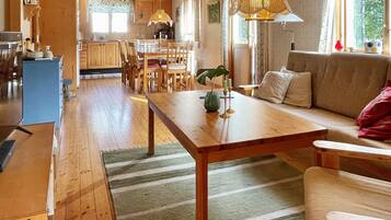 A cozy living room with a wooden table, sofa, and a kitchen in the background.
