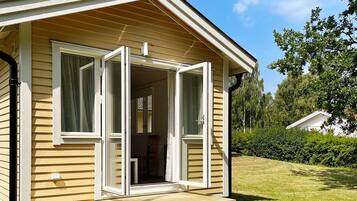 A single-story wooden house with a front porch and a sliding glass door.