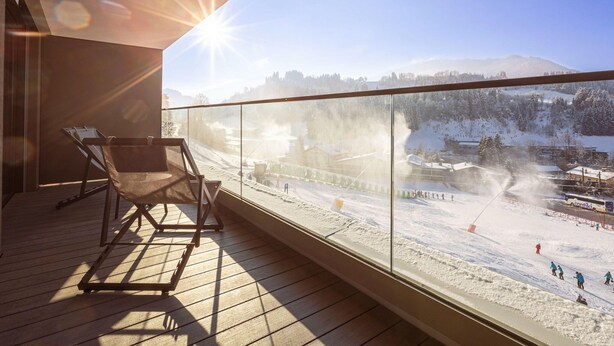 Ein Balkon mit freiem Blick auf eine verschneite Landschaft und ein Skigebiet.