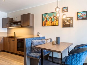 Eine moderne Küche mit Holzschränken, einem eingebauten Backofen und einem Essbereich mit Bank und Tisch.