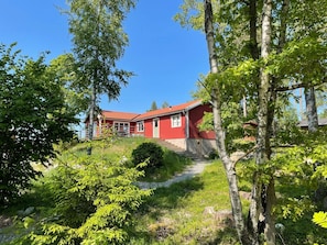 A red building with a sloped roof, surrounded by trees and greenery. - 4 Star Holiday Home in Akersberga (Akersberga)