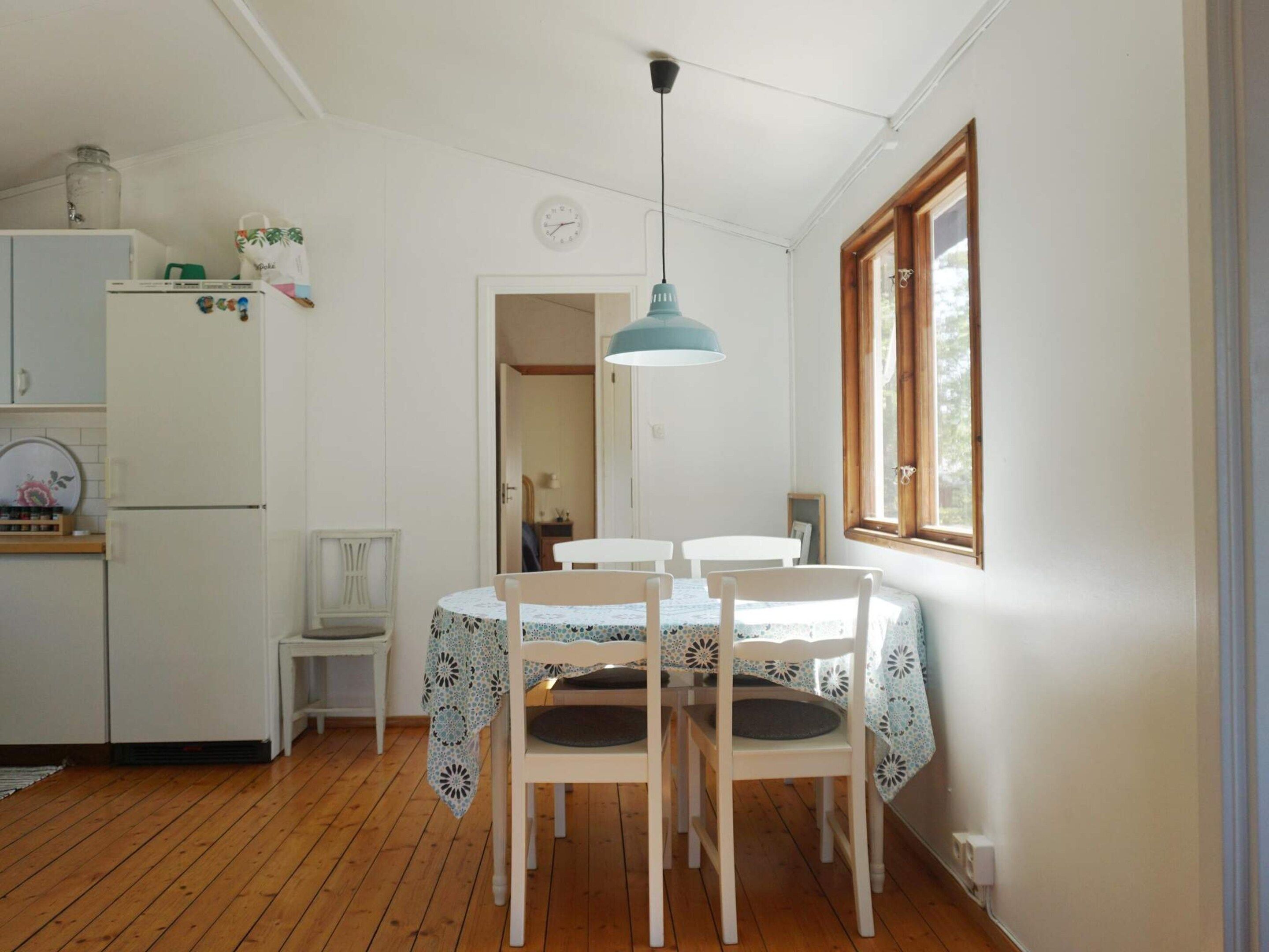 A dining area with a table and chairs, a hanging light fixture, and a window with a view.