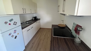 A small kitchen with white cabinets, a refrigerator, a sink, and a stove.