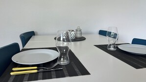 A dining table set with plates, cutlery, and glasses, with a patterned placemat and a salt and pepper set on the table.