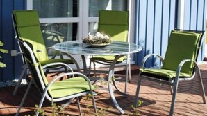 An outdoor patio with a round glass table and four green chairs. - Holiday Apartment Alleblas (Geldern)