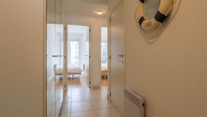 A hallway with a bed, a radiator, and a life preserver on the wall. - Apartment in Nieuwpoort by the Seafront (Koksijde)
