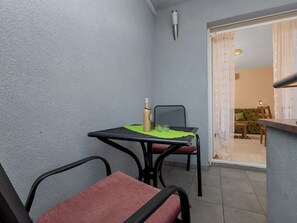 A small balcony with a table and chairs, a bottle, and a green mat. - Apartments Villa Juric - One Bedroom Apartment With Balcony - 4 (Baska Voda)