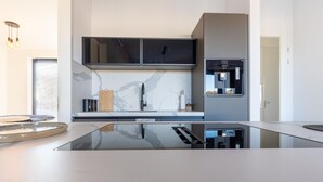 Una cocina moderna con una isla central, armarios negros y un horno empotrado.