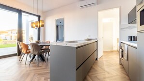 Una cocina moderna con una isla central, un comedor con sillas y vistas al exterior.
