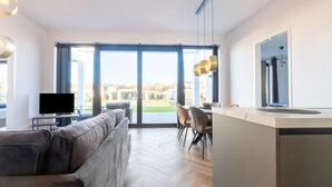 Una sala de estar moderna con sofá, comedor y isla de cocina.