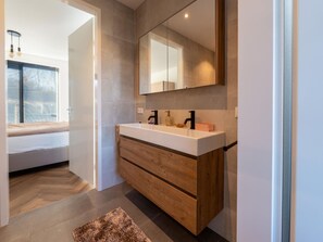 A modern bathroom with a large mirror, wooden vanity, and a window with blinds. - Cozy Villa With Lakeside Views (Zeewolde)