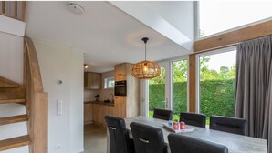 A modern kitchen with wooden cabinets, a dining area with a table and chairs, and a staircase. - Holiday Home Near Beach Burgh-haamstede (Burgh-Haamstede)