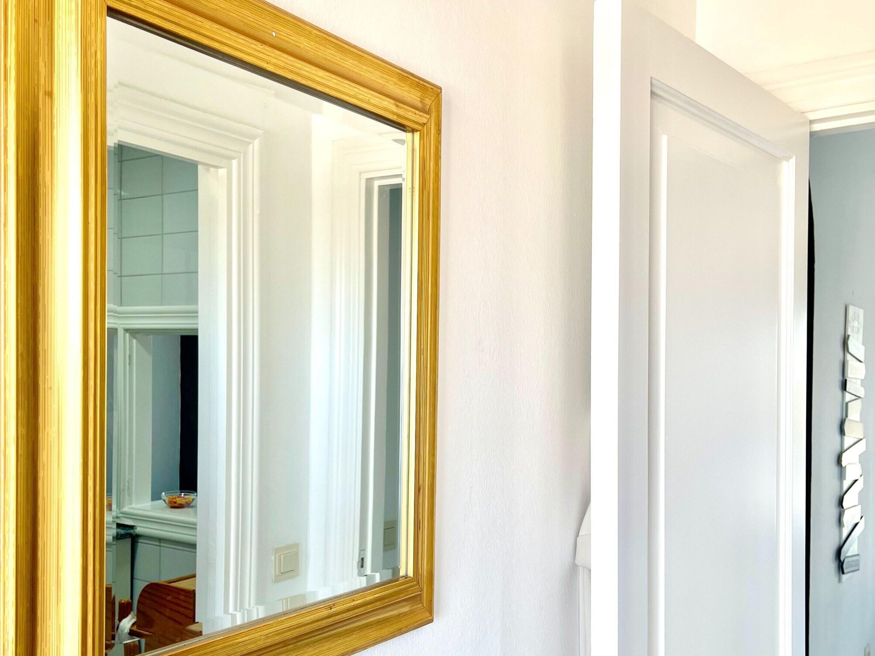 A room with a large mirror, a door, and a wall-mounted light fixture.