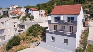 A multi-story residential building with a red-tiled roof, white walls, and a balcony on the upper floor. - Apartment Stipic Omis - Three Bedroom Apartment With Terrace (Omis)