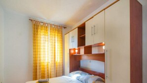 A bedroom with a bed, two pillows, a bedside table, and a wardrobe. - Apartment Stipic Omis - Three Bedroom Apartment With Terrace (Omis)