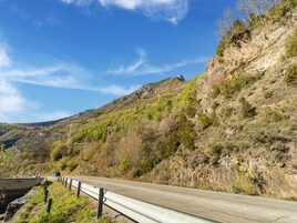 Una carretera con barandillas, una montaña al fondo y vegetación escasa.