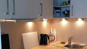 A modern kitchen with white cabinets, a stainless steel sink, a coffee maker, and a toaster.