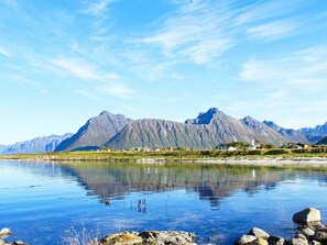 En stilla sjö med berg i bakgrunden och en liten bebyggelse på andra sidan vattnet.