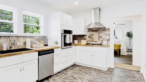 A modern kitchen with white cabinetry, a built-in oven, and a stone backsplash.