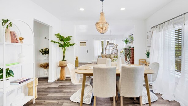 A dining area with a wooden table, white chairs, and a hanging light fixture.