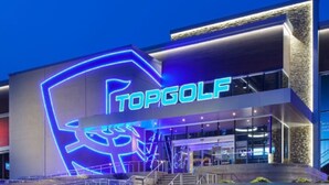 A modern building with a prominent 'TOPGOLF' sign, featuring a stylized golf club logo.