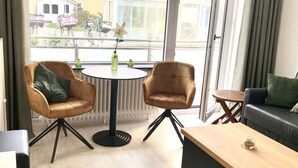 Moderni olohuone, jossa on kaksi nahkaista nojatuolia, pyöreä ruokapöytä ja puinen sohvapöytä.