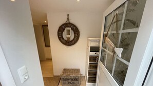 A narrow hallway with a wicker basket labeled 'NEW YORK 1928' and a wicker wall hanging with text. - Balticliving Modern Retreat (Timmendorfer Strand)
