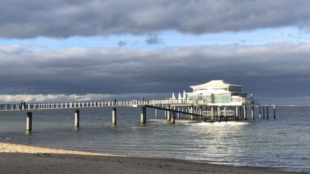 A pier extending into the water with a building at its end. - Balticliving Modern Retreat (Timmendorfer Strand)