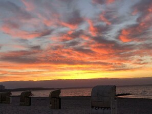 A beach with wicker chairs and a sunset. - Balticliving Modern Retreat (Timmendorfer Strand)