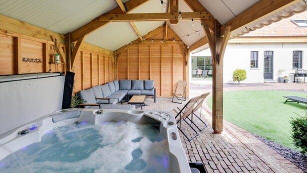 Een bubbelbadgedeelte met een houten terras, een zithoek en uitzicht op het omliggende landschap.
