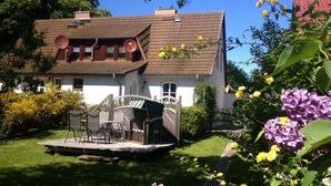 A two-story house with a tiled roof, satellite dishes, and a small deck with outdoor furniture. - Holiday Apartment "kati" (Lancken-Granitz)