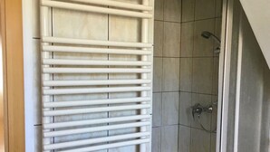 A bathroom with a white towel rack, tiled walls, and a shower area. - Ferienwohnung in Klutz an der Ostsee (Klütz)