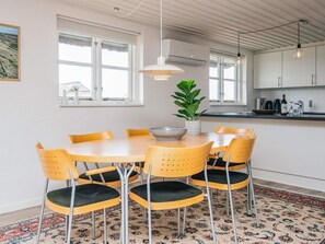 A dining area with a round table, six chairs, a potted plant, and a hanging light fixture. - 7 Person Holiday Home in Ulfborg (Ulfborg)