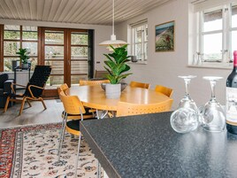 Un comedor con una mesa redonda de madera, sillas amarillas, una planta en maceta y una lámpara colgante.