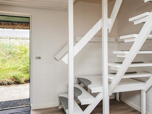 Un escalier en colimaçon blanc, avec de nombreuses marches menant vers le haut, est placé à côté d’une porte dont le cadre est vert.