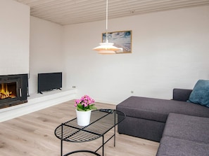 A living room with a fireplace, a television, a sofa, and a hanging light fixture.
